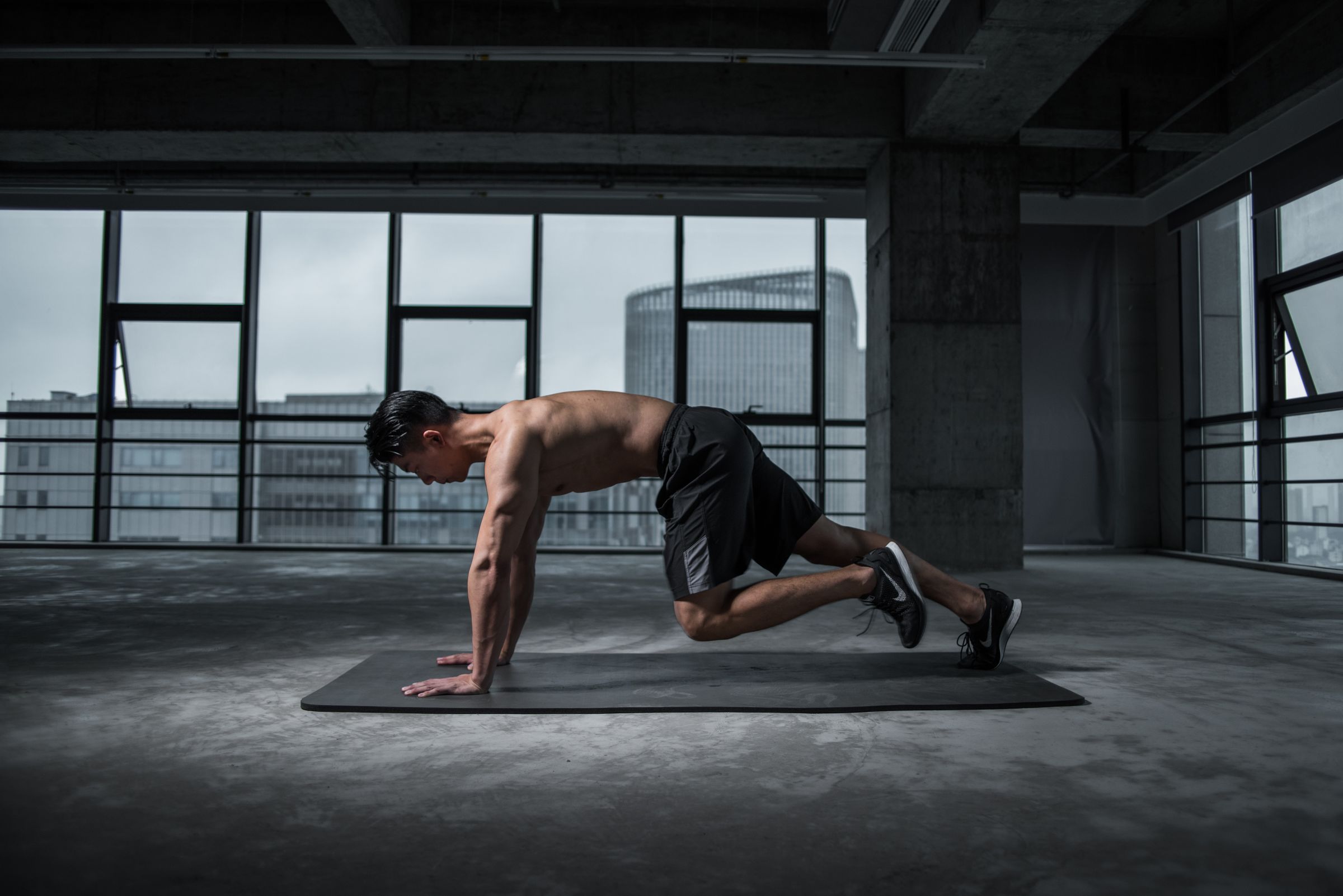 Shirtless athlete training on the floor in an industrial gym loft